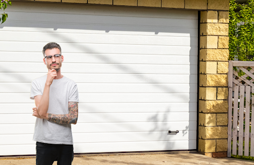 A man in deep thought standing in front of a garage door.
